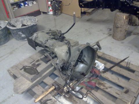 1984 Ford Bronco - A disassembled transmission sits on pallets in a workshop environment, suggesting repair or rebuilding.