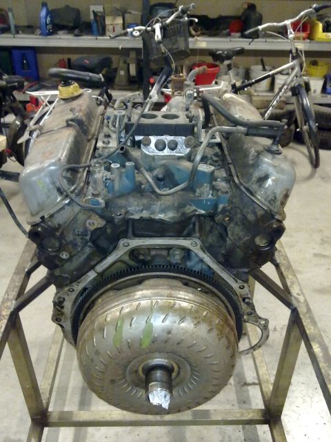1984 Ford Bronco - Engine and torque converter assembly displayed on a metal stand, likely for rebuild or maintenance.