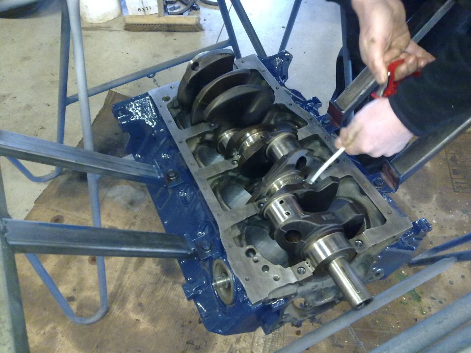 Engine block with crankshaft being worked on. Someone is cleaning or lubricating the crankshaft bearings