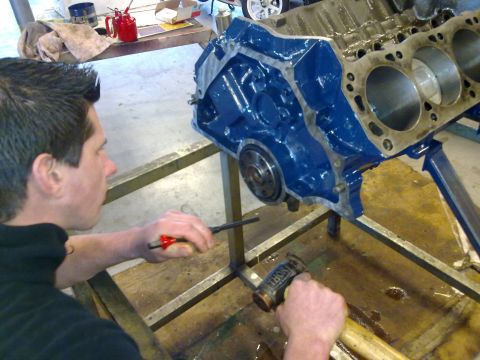 1984 Ford Bronco - Engine block assembly in progress with tools and a person working on it.