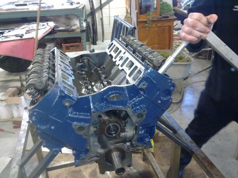 1984 Ford Bronco - A blue engine block is being worked on in a garage setting. The engine appears to be partially disassembled.