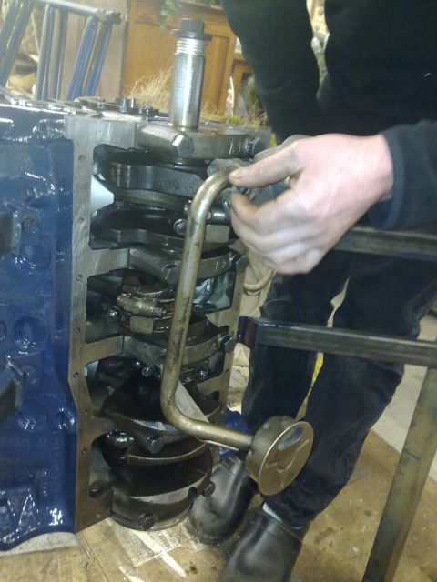 1984 Ford Bronco - Close-up of an engine block undergoing maintenance, focusing on the crankshaft and oil pump assembly.