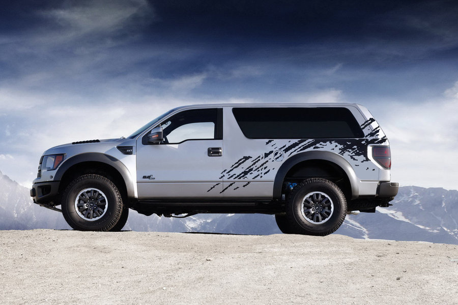 Silver SUV with black splatter graphics on the side, parked on a dirt hill with mountains in the background