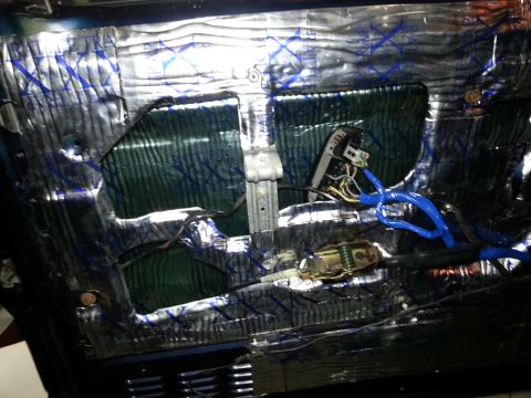 1994 Ford Bronco - Interior view of a car door with sound deadening material installed around the window mechanism and wiring.