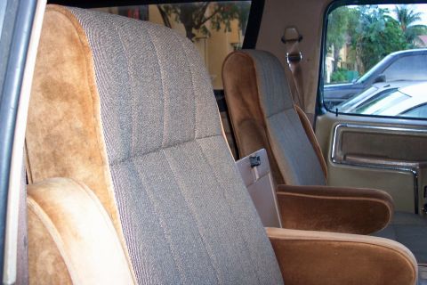 1986 Ford Bronco - The interior of this 1986 Ford Bronco features patterned fabric seats with brown velour accents and armrests.