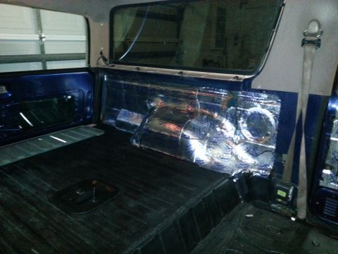 1994 Ford Bronco - The rear interior of a blue vehicle shows sound dampening material being applied to the wall.
