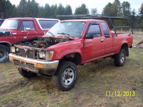 1991 Toyota Pickup/SR5 - A red 1991 Toyota Pickup SR5 is parked outside with its hood open, revealing engine damage.