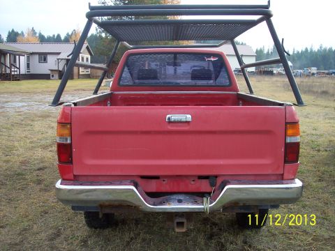 1991 Toyota Pickup/SR5 - Rear view of a red pickup truck with a large metal rack installed in the bed.