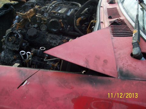 1991 Toyota Pickup/SR5 - The engine compartment of a red vehicle shows extensive fire damage, with the hood propped open.