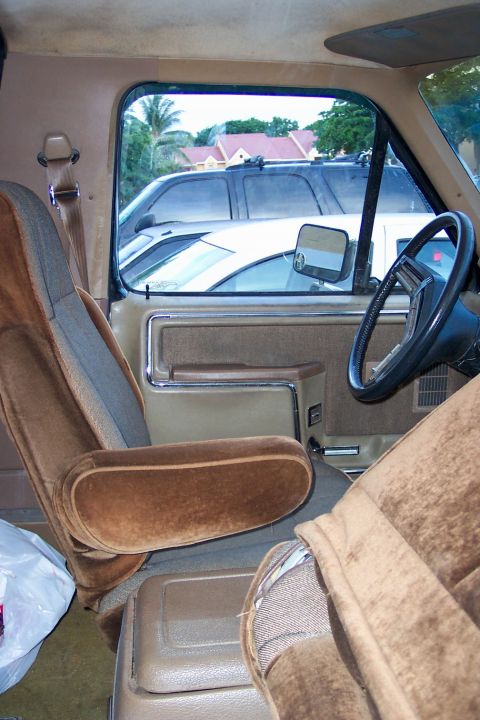 1986 Ford Bronco - The interior of a 1980s SUV, with a view of other vehicles and houses through the window.