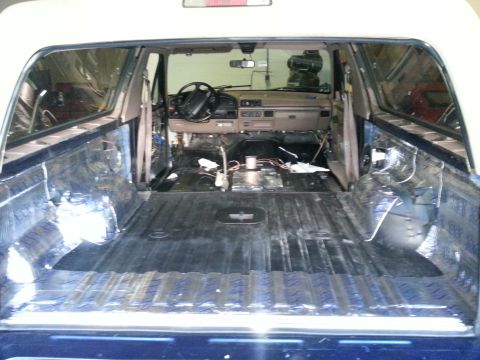1994 Ford Bronco - The interior of a 1994 Ford Bronco shows a stripped-down cabin and cargo area, with insulation and wiring exposed.