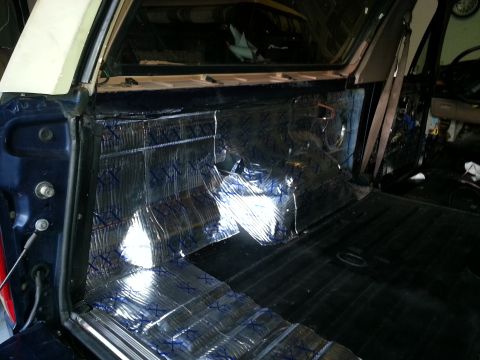 1994 Ford Bronco - Sound deadening material is being applied to the interior panels of a vehicle, likely for noise reduction.