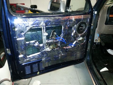 1994 Ford Bronco - The interior of a blue vehicle's door is shown with sound deadening material and exposed wiring after the panel removal.