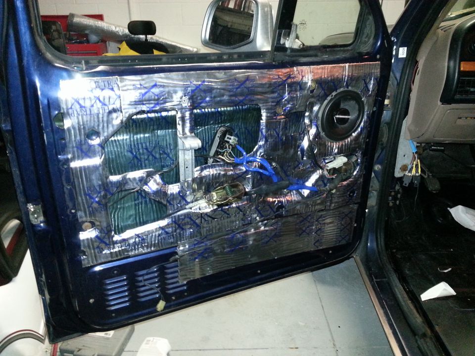 Blue car door interior with sound deadening material, exposed wiring, and a speaker. The door panel is removed