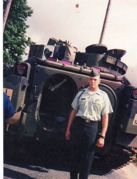 1982 Ford Bronco - A soldier poses in front of a military vehicle, possibly a tank or armored personnel carrier.