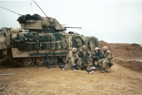 1982 Ford Bronco - Soldiers take a break next to a military vehicle, which appears to be a Bradley Fighting Vehicle.