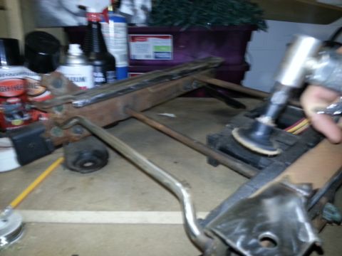 1994 Ford Bronco - Working on a metal frame part with a grinder. Tools and supplies are visible in the background.