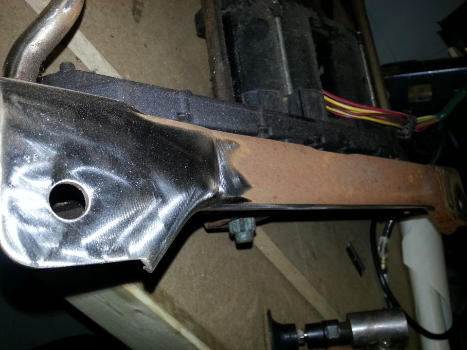 Seat bracket with chrome and rust, showing wiring harness and bolt