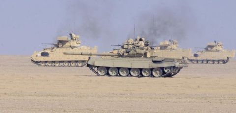 1982 Ford Bronco - Military tanks are shown in formation across a desert terrain under a clear sky.