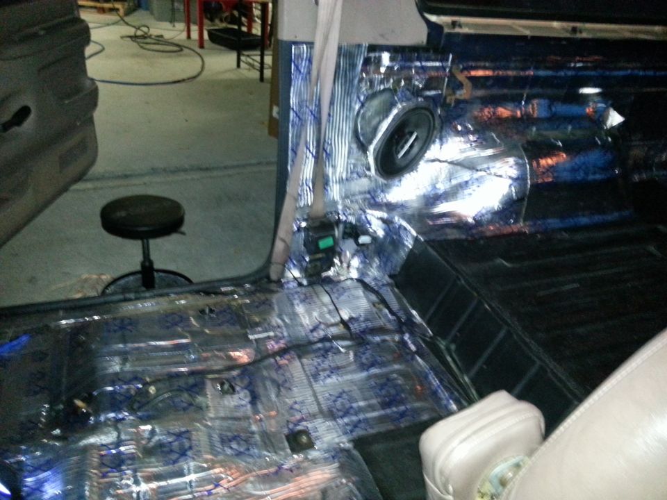 Car interior with soundproofing material on floor and doors, speaker visible
