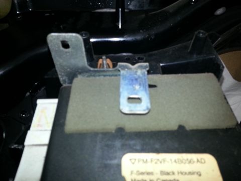 1994 Ford Bronco - Close-up of an interior vehicle part, showing a metal bracket and a label with text.