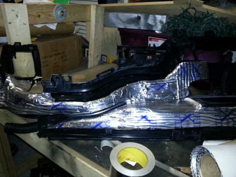 1994 Ford Bronco - A vehicle dashboard component covered in silver sound deadening material with blue X markings is shown.