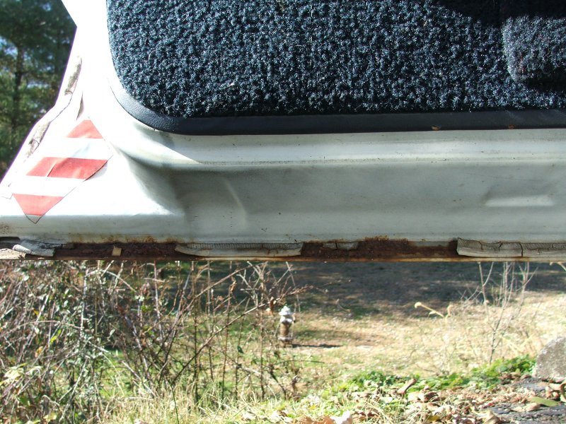 close-up of rusty car door sill with black carpet above