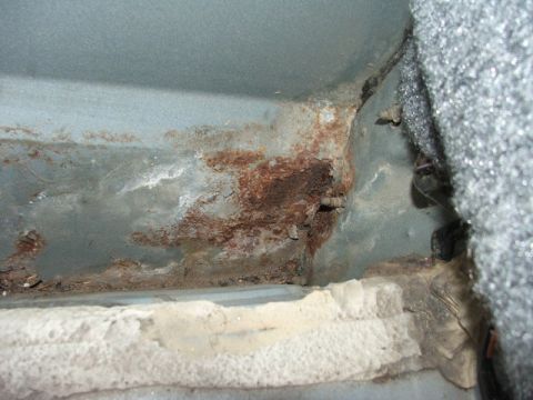 1988 Ford Crown Victoria LTD - Corroded metal interior panel shows significant rust damage and is adjacent to foam padding.