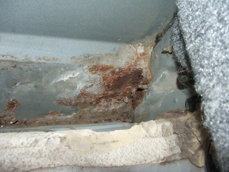 Rusted metal interior panel with visible corrosion and foam padding