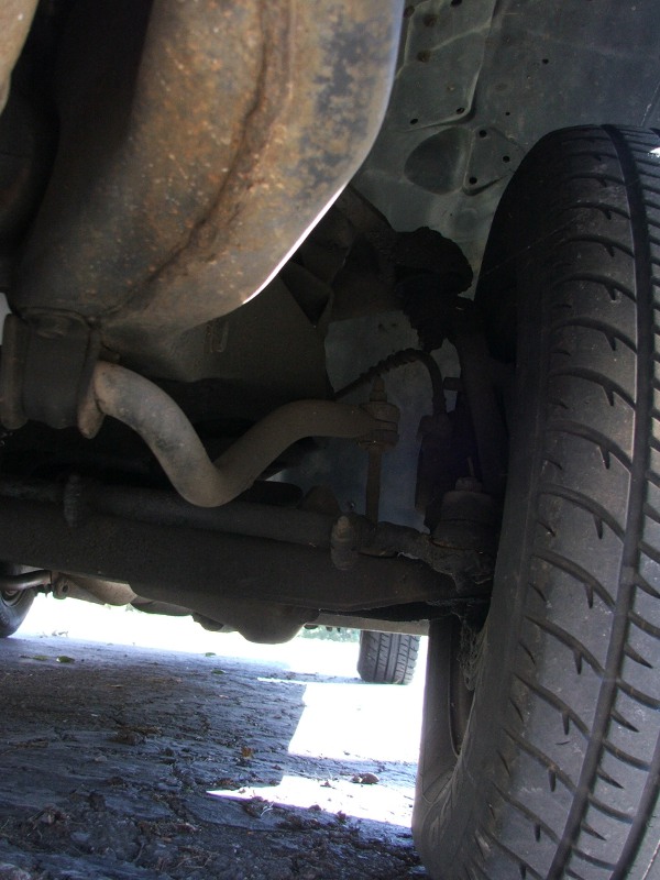 Undercarriage view showing exhaust pipe, suspension components, and tire