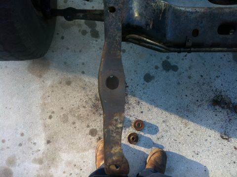 1979 Ford Bronco - A close-up view of a rusty vehicle frame component and associated hardware resting on a concrete surface.