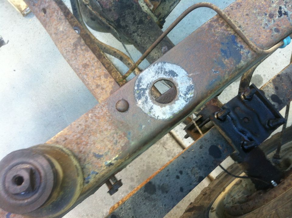 Rusty vehicle frame and suspension parts, SuperMotors.net logo visible
