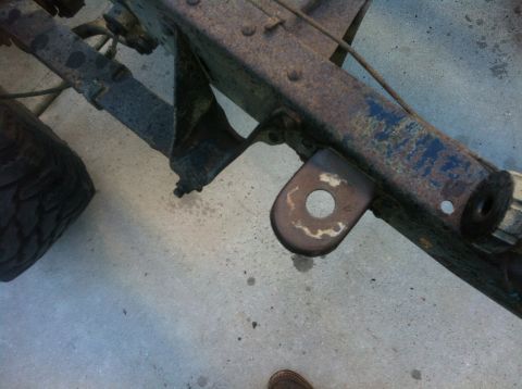 1979 Ford Bronco - Close-up of a heavily rusted vehicle frame and suspension components, with a tire in the background.