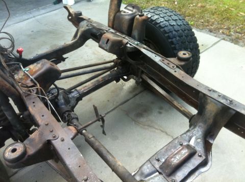 1979 Ford Bronco - The frame and suspension components of a vehicle are shown, with a tire in the background.