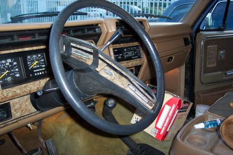 1986 Ford Bronco - The interior of a 1986 Ford Bronco shows woodgrain trim on the dashboard and door panels, along with the steering wheel and gauges.