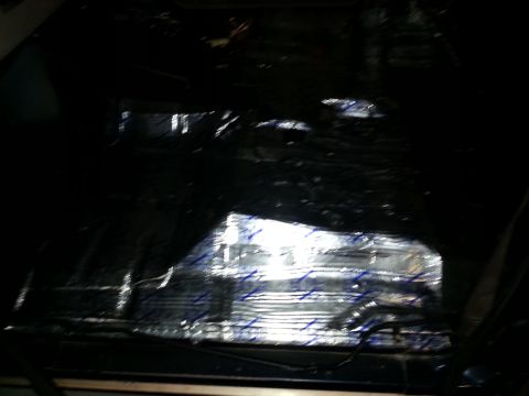 1994 Ford Bronco - The interior floor of a vehicle is covered with sound deadening material and some wiring is exposed.