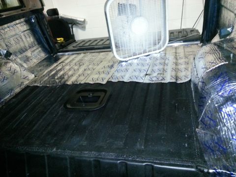 1994 Ford Bronco - The interior of a vehicle is being worked on, with sound deadening material applied and a fan present.