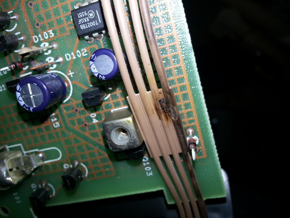 Circuit board with burnt wires and capacitors, close-up view