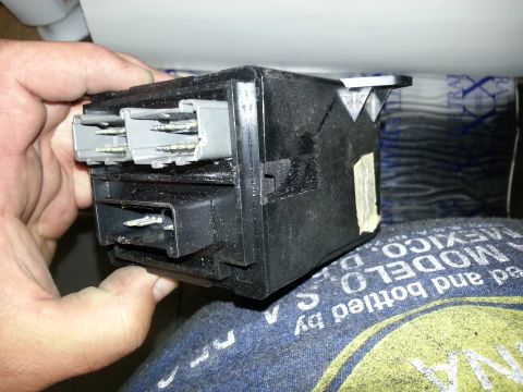 1994 Ford Bronco - A hand holds a black electrical component with multiple gray connectors, likely a car part.