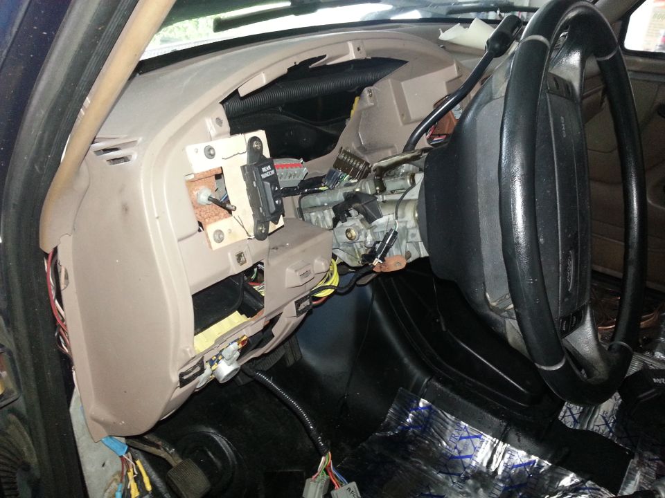 car dashboard disassembled, showing wires and steering column