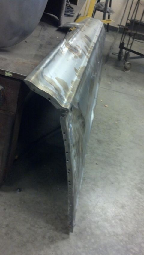 1964 Ford Fairlane - A bare metal car door panel is shown, likely in a workshop setting, with visible signs of bodywork and repair.