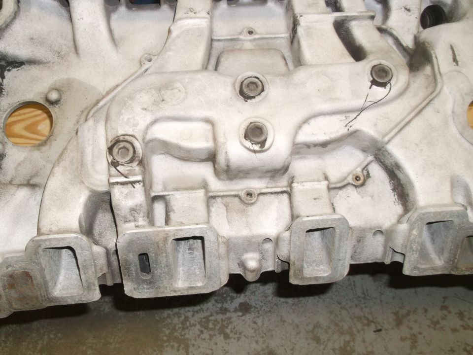 Close-up of an engine intake manifold with multiple runners and bolt holes