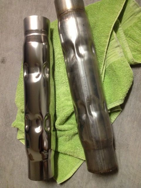 2013 Ford Mustang - Two exhaust pipes, one shiny and one used, rest on a green towel next to a concrete surface.