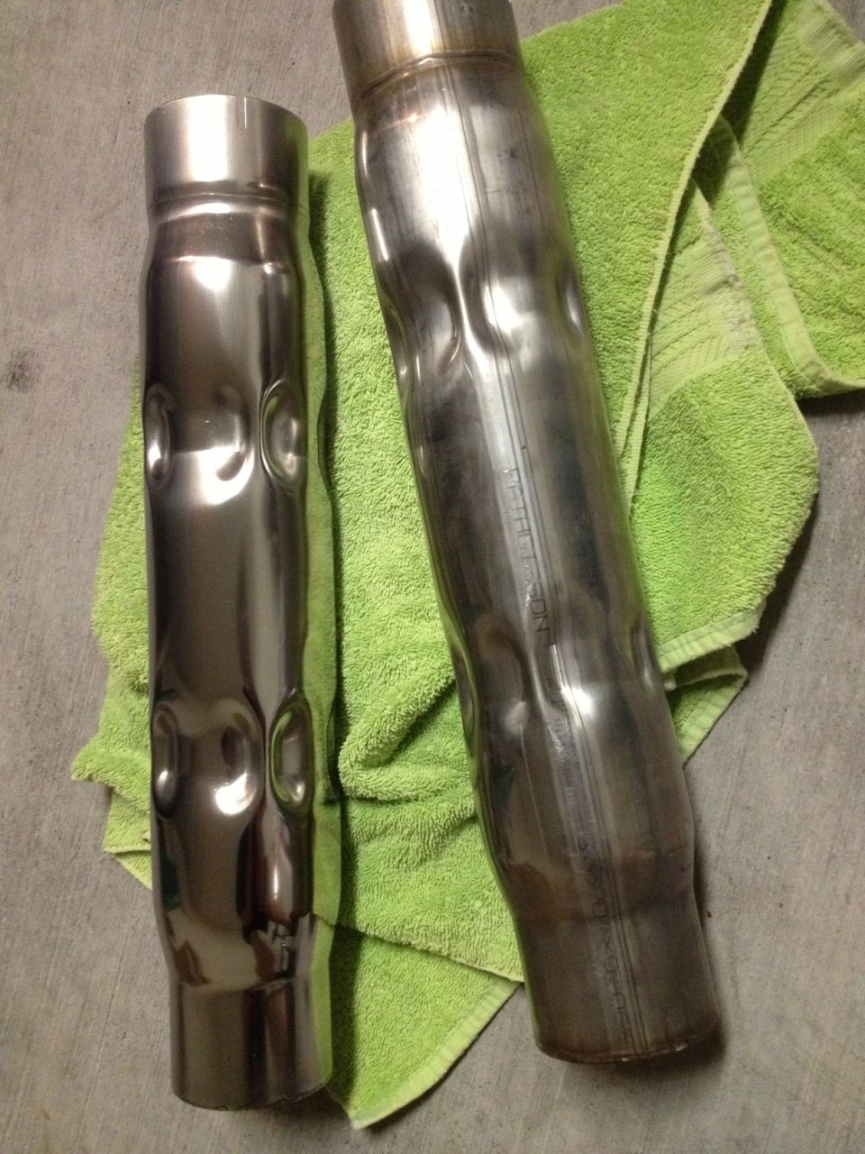 Two dented exhaust pipes on a green towel