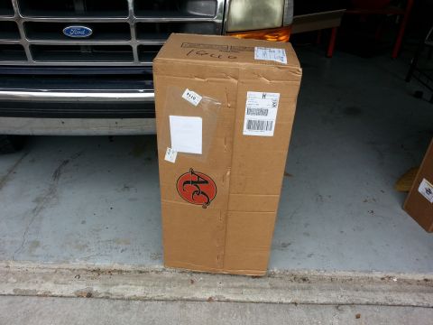 1994 Ford Bronco - A large cardboard box with shipping labels and an AC logo is placed in front of a Ford truck.