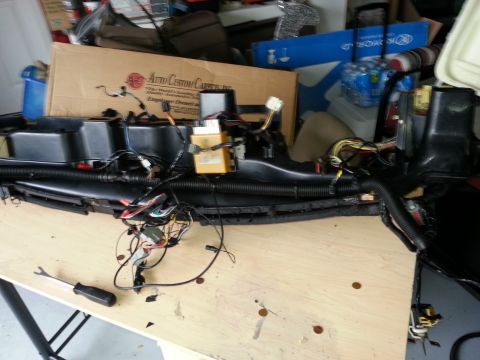 1994 Ford Bronco - A disassembled dashboard wiring harness is laid out on a workbench, showing complex electrical connections and a yellow control module.