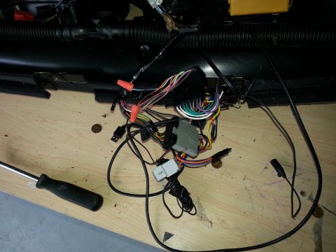 1994 Ford Bronco - A car's wiring harness, disconnected and laid out on a wooden surface, with a screwdriver nearby.