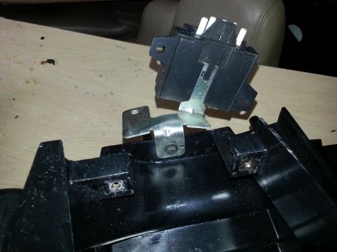 1994 Ford Bronco - Close-up of a disassembled automotive electrical part and dashboard trim, likely for repair or replacement.