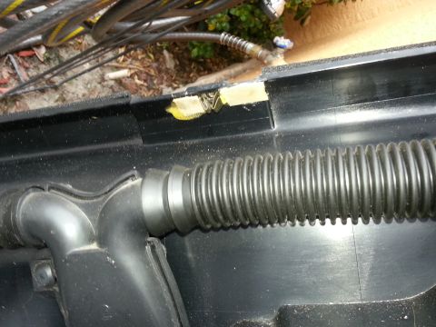 1994 Ford Bronco - Close-up of a corrugated hose connected to black plastic trim, with yellow tape on the trim.