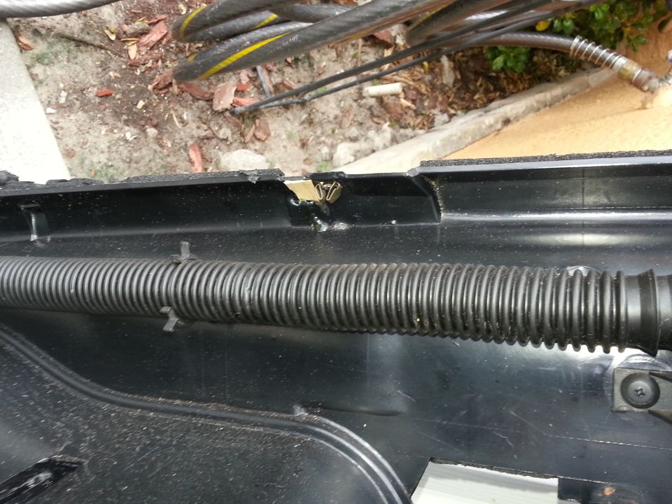 Close-up of black plastic dashboard trim with a corrugated wire loom running through it. Some wires are visible above